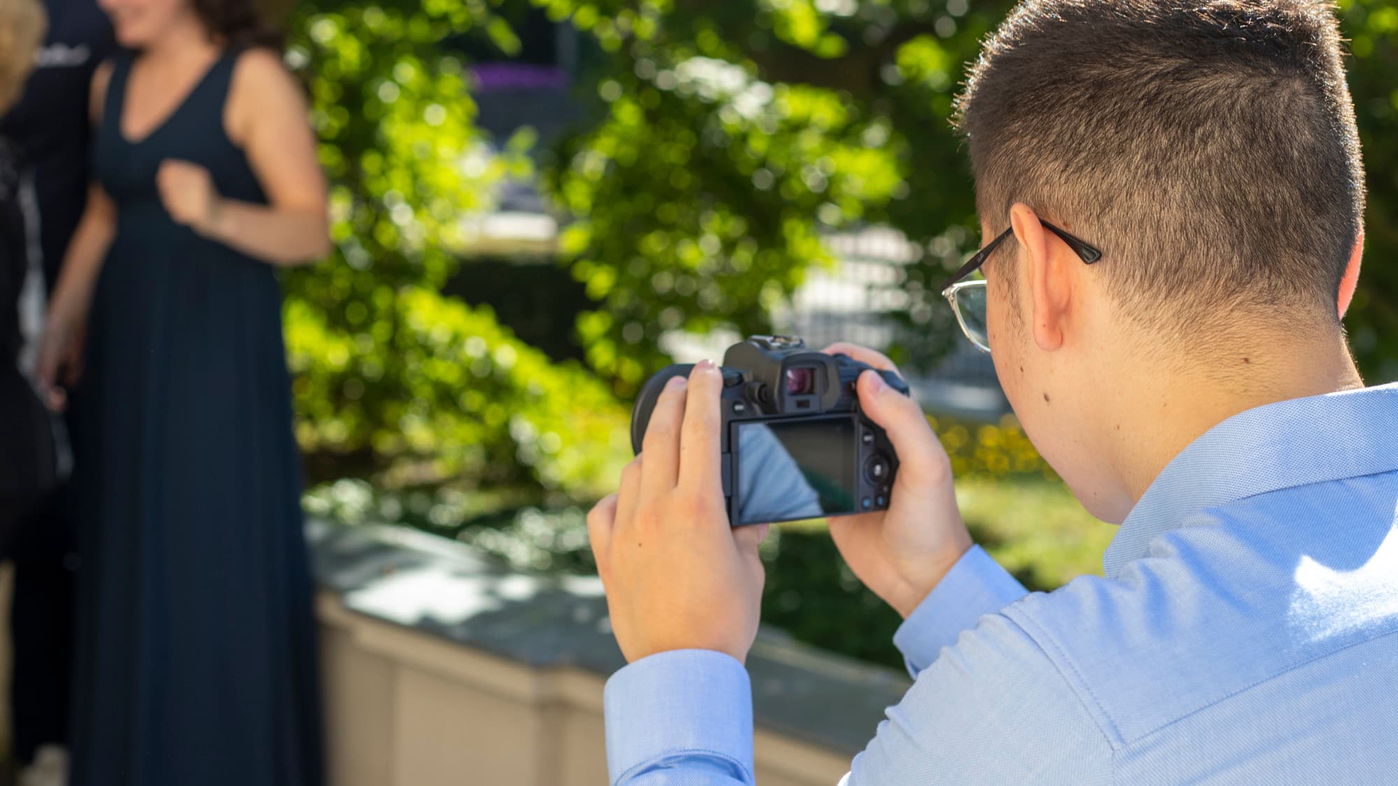 Hochzeitsfotograf fotografiert mit Kamera bei einer Hochzeit im Freien