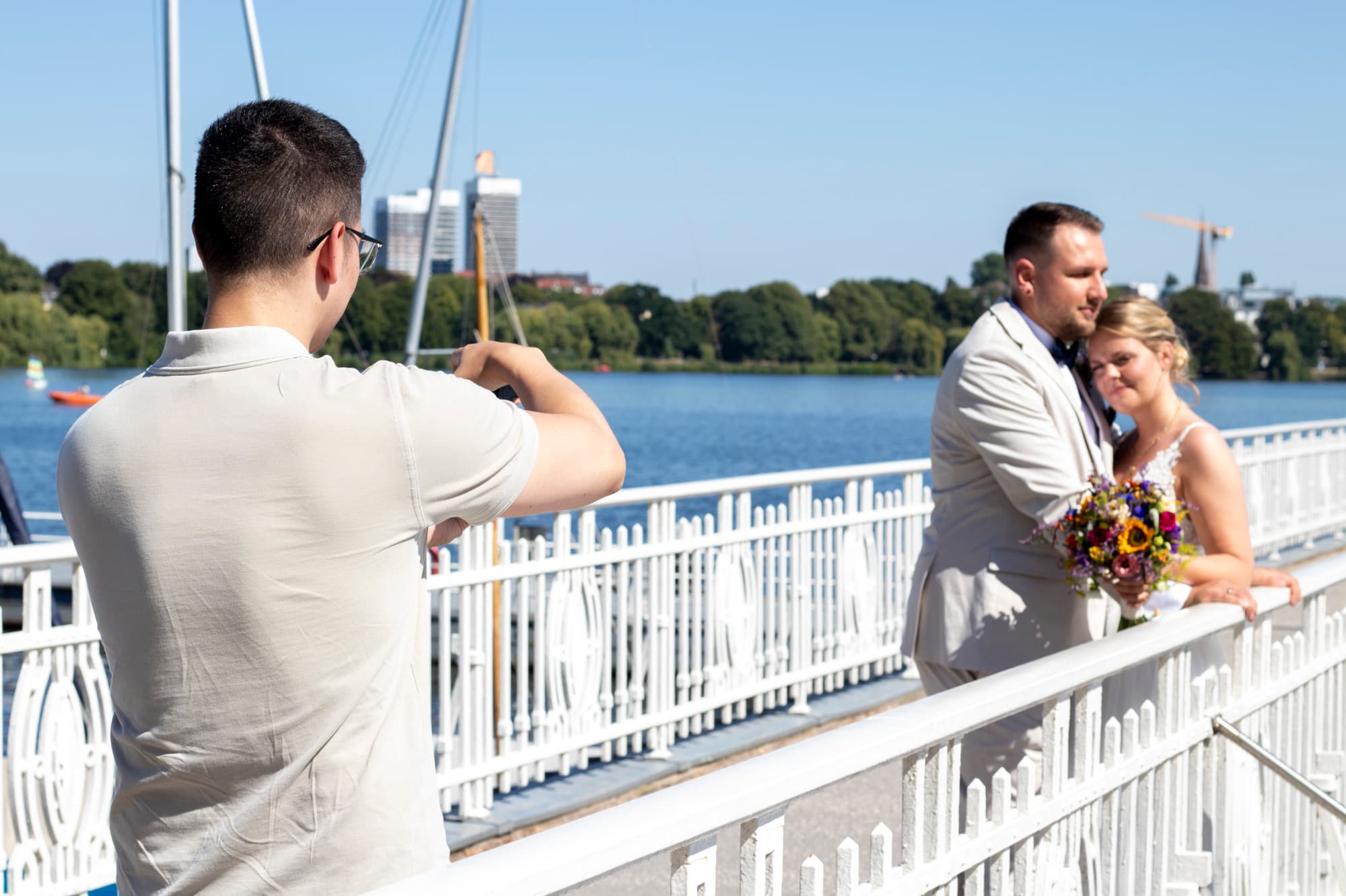 Hochzeitsfotograf fotografiert das Brautpaar auf einer Brücke am Wasser